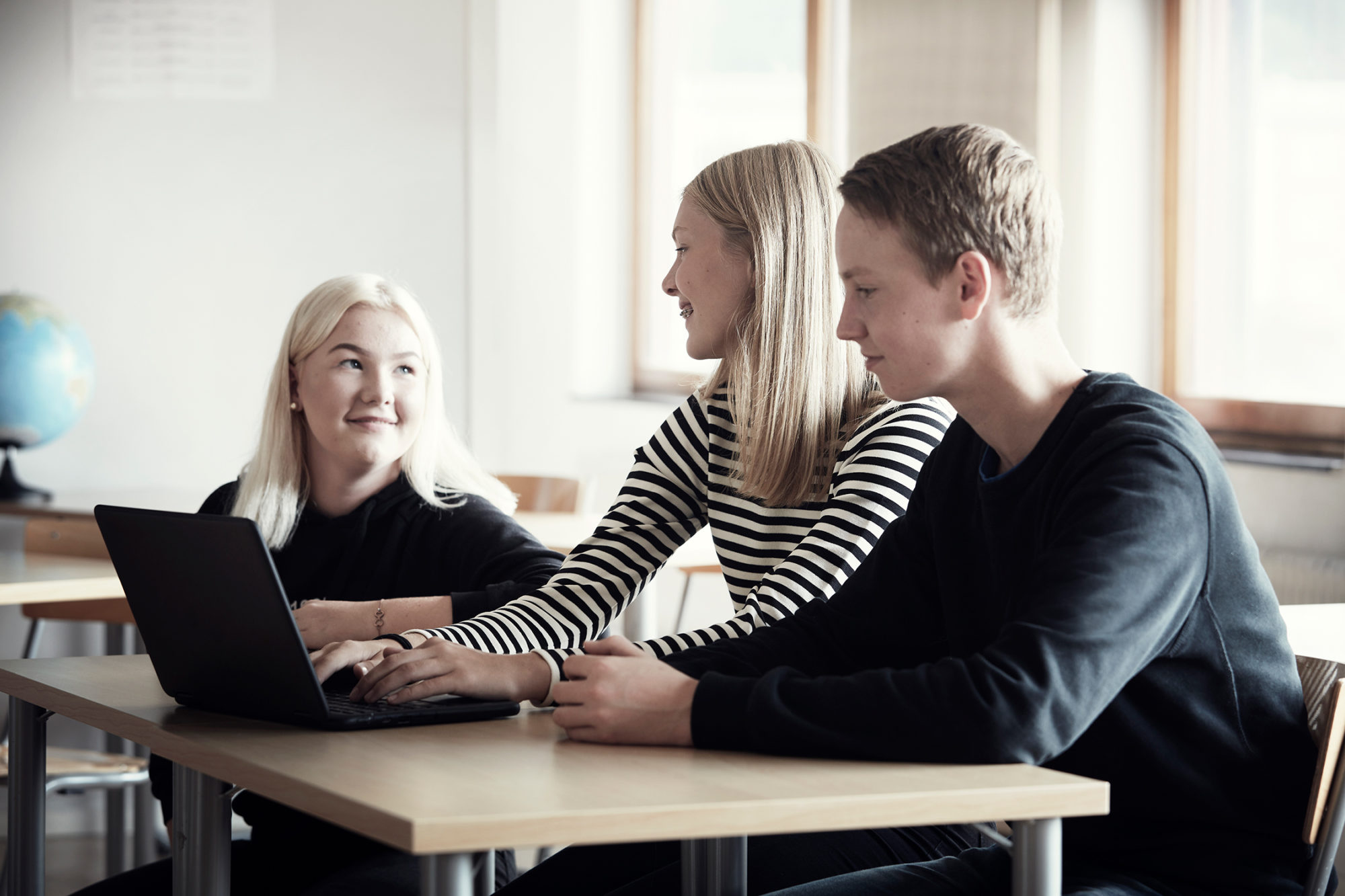 Tre elever sitter vid skolbänken